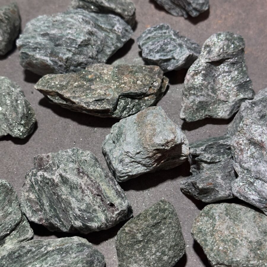 close-up of a raw fuchsite with shimmering green tones and uneven surface