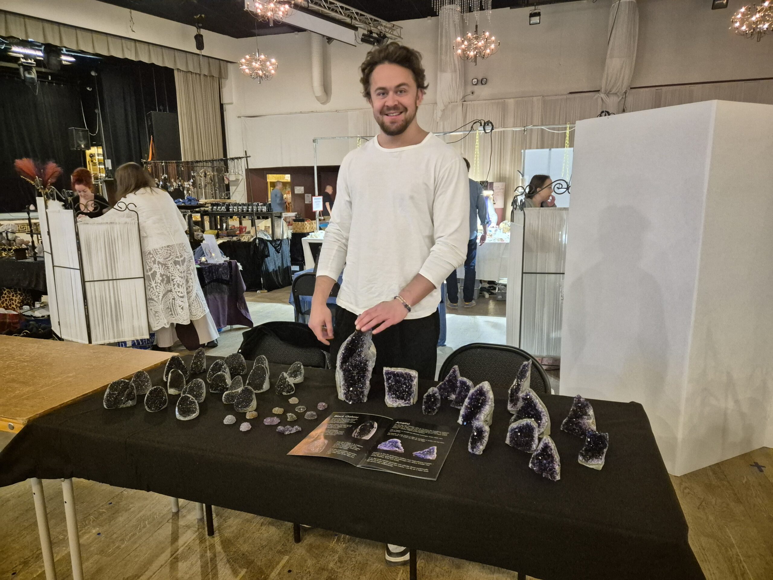 Man säljer kristaller på marknad i utställningshall.