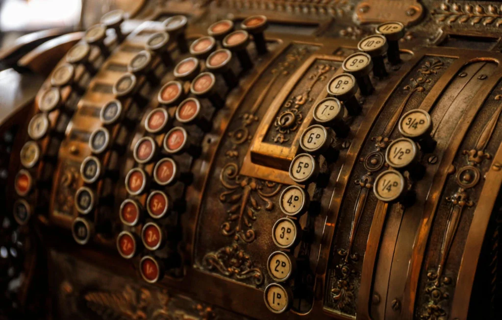 Gammal kassaapparat med dekorerade tangenter och detaljer.